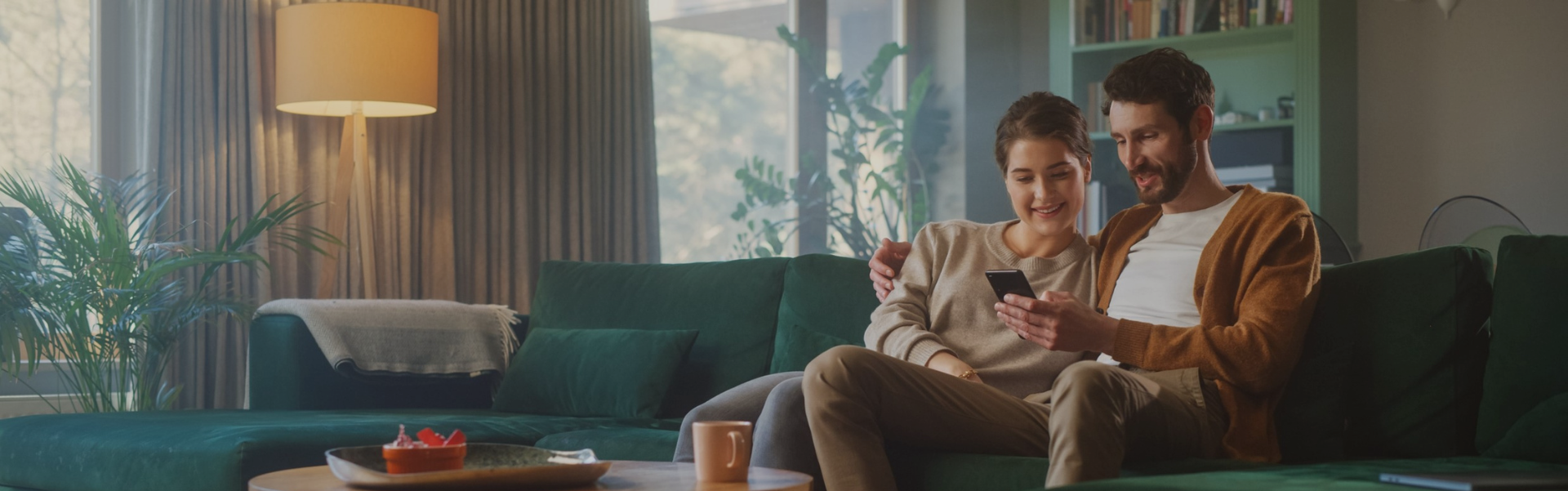 Paar auf der Couch liest gemeinsam eine Premium Story am Smartphone